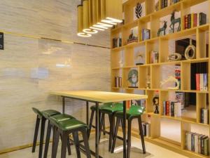 Jiang'anにあるCity Comfort Inn Wuhan Yuanlin Road Metro Stationの本棚付きの部屋(テーブル、緑の椅子4脚付)