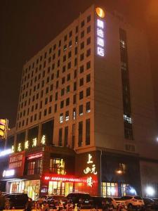 a tall building with a sign on it at night at JTOUR Inn Wuxi Railway Station Shangmadun Metro Station in Wuxi