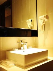 a bathroom with a white sink and a mirror at JTOUR Inn Wuxi Railway Station Shangmadun Metro Station in Wuxi
