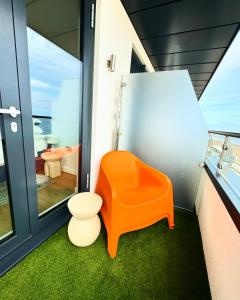 ein Badezimmer mit einem orangenen Stuhl und einem WC in der Unterkunft Stunning Beach Front Apartment with Sea views, FREE Parking & Balcony in Ramsgate