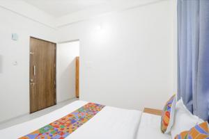 a bedroom with a bed and a wooden door at FabHotel Blue Ocean MNJ Resort in Nashik