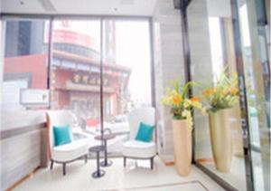 una habitación con 2 sillas y una ventana con flores en City Comfort Inn Changchun Chongqing Road Huolicheng, en Changchún