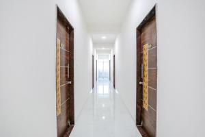 a corridor with two wooden doors and a hallway with white walls at FabHotel Blue Ocean MNJ Resort in Nashik
