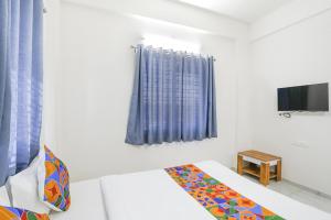 a white room with a bed and a tv at FabHotel Blue Ocean MNJ Resort in Nashik