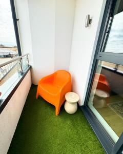 eine orangefarbene Bank in einem Zimmer mit Fenster in der Unterkunft Stunning Beach Front Apartment with Sea views, FREE Parking & Balcony in Ramsgate