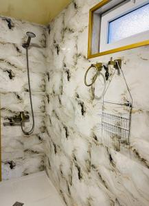 a shower in a bathroom with a marble wall at Guest house poligloti in Tʼelavi