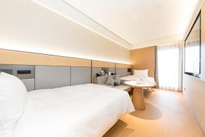 um quarto com uma grande cama branca e uma mesa em JI Hotel Hangzhou Qianjiang New City Civil Center em Hangzhou