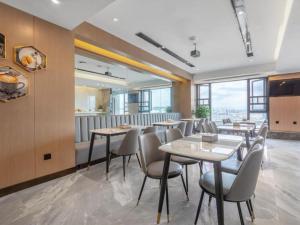 a restaurant with tables and chairs and windows at Gya Hotel Kunming Zijin Center Xiaodongcun Metro Station in Kunming