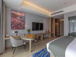 um quarto com uma cama, uma mesa e uma televisão em Gya Hotel Kunming Zijin Center Xiaodongcun Metro Station em Kunming