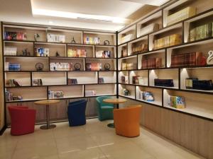 a library with two tables and shelves with books at Hanting Hotel Shenzhen Longgang Nanlian Metro Station in Longgang