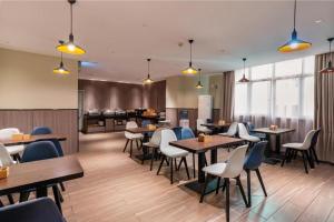 a restaurant with tables and chairs and a kitchen at Hanting Hotel Guangzhou North Railway Station in Huadu