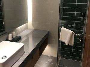 W łazience znajduje się umywalka i przeszklony prysznic. w obiekcie Green Tree Inn Tianjin Jinnan Linshijun University of Finance and Economics w mieście Huidui