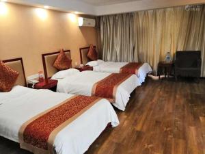 a hotel room with three beds and a television at Super 8 Hotel Jinan West Gate of Long Distance Bus Station in Beiyuan