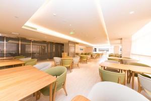 Ji Hotel Jinan 2nd Ring Xi Road في Luokou: كافتيريا بطاولات وكراسي خشبية وطاولات وكراسي