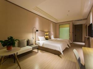 ein Hotelzimmer mit 2 Betten und einem grünen Bildschirm in der Unterkunft Hanting Hotel Xian Changqing Road Metro Station in Xi'an