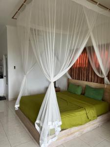 1 dormitorio con 1 cama verde con dosel en Azona Greens Uluwatu, en Uluwatu