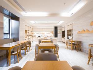 una sala da pranzo con tavoli e sedie in legno di Ji Hotel Shanghai Wuwei Dong Road Metro Station a Shanghai