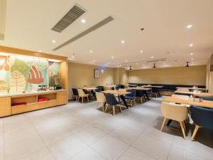 Hanting Hotel Jinan Guo Branch في جينان: مطعم فيه طاولات وكراسي في الغرفة