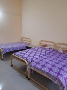 2 camas en una habitación con mantas moradas en Swami Sahvas Homestay, en Kudāl