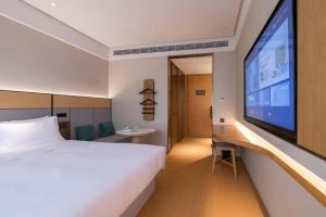 a hotel room with a bed and a large tv at Ji Hotel Shanghai Yangpu Gym in Shanghai
