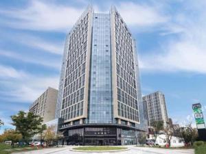 a tall glass building with a curve in front of it at Ji Hotel Jiaxing Shanshan Impression Plaza in Jiaxing