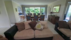 a living room with a couch and a dining room at Rainforest Deluxe Bungalow in Port Macquarie