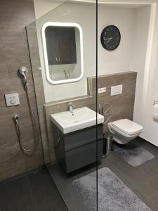 a bathroom with a sink and a toilet and a clock at TOP Ferienwohnung in Bad Urach