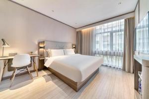 um quarto com uma grande cama branca, uma secretária e uma janela em Hanting Hotel Hangzhou East Railway Station Airport Road em Hangzhou