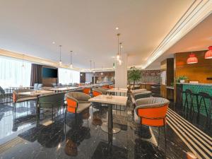 um restaurante com mesas e cadeiras num quarto em Hanting Hotel Nanjing Jiangning Binjiang Development Zone Park em Qingxiu