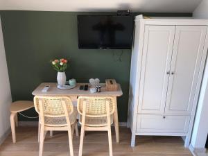 a dining room table with two chairs and a white cabinet at My Little Village in Poiana Mărului