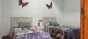 ロダルキラルにあるLa Belleza de Rodalquilarの蝶が壁に描かれた部屋のベッド2台