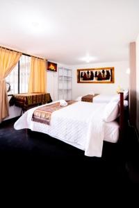 um quarto com uma grande cama branca e uma janela em Tourist house 1 em Otavalo