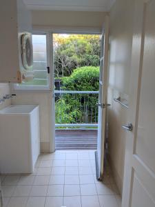 a bathroom with a door open to a balcony at Rainforest Deluxe Bungalow in Port Macquarie +57 photos