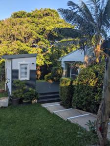 a house with a palm tree next to a yard at Rainforest Deluxe Bungalow in Port Macquarie