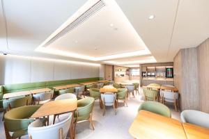 restauracja z drewnianymi stołami i zielonymi krzesłami w obiekcie Ji Hotel Shanghai Daning International w Szanghaju