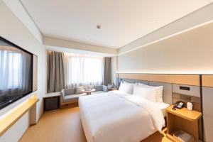 Pokój hotelowy z dużym łóżkiem i telewizorem w obiekcie Ji Hotel Shanghai Daning International w Szanghaju