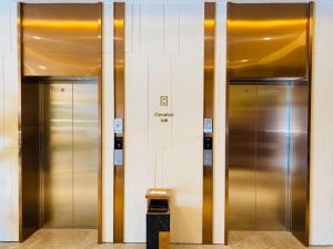 Dos ascensores metálicos en un edificio con una basura en Lavande Hotel Changchun Gaoxin Jilin University, en Changchún