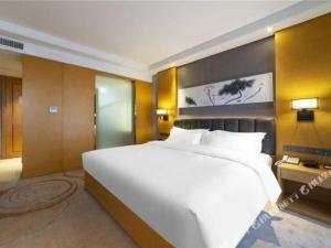 - un grand lit blanc dans une chambre d'hôtel dans l'établissement Borrman Hotel Jinan Yijia Exhibition Center Laotun Metro Station, à Jinan