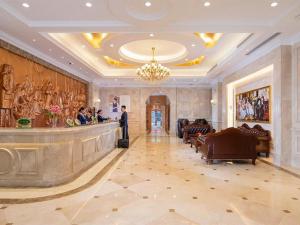un homme debout dans le hall de l'hôtel avec un bar dans l'établissement Vienna Hotel Zhengzhou Only Henan Movie Town, à Zhongmou