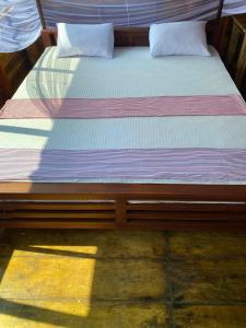 1 cama con marco de madera en una habitación en Surf Beach Hotel, en Arugam Bay