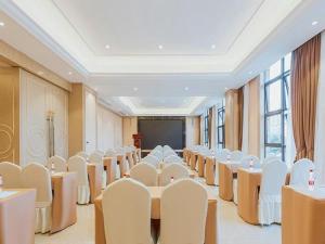 a conference room with tables and chairs and a screen at Vienna Hotel Chongqing Jiangjin Shuangfu in Zouma
