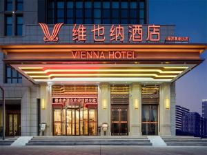 Vienna Hotel Tianjin Binhai New District Ocean High-Tech Zone في Binhai: فندق venna أمامه لافتة نيون