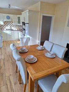una mesa de madera con sillas blancas y una cocina en 'Grange Hideaway' Town Centre (Sleeps 6), en Omagh