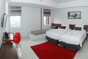 Habitación blanca con 2 camas y alfombra roja. en HI HOTEL SENEN en Yakarta