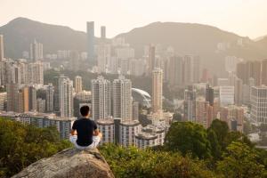 a man sitting on a rock overlooking a city at J Link Hotel in Hong Kong