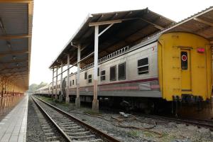 a yellow and silver train sitting at a train station at RoomQuest Chiang Mai Tha Sala in Chiang Mai