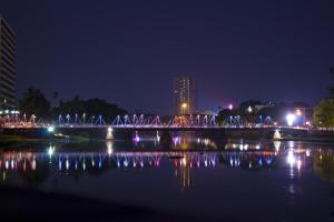 a bridge over a body of water at night at RoomQuest Chiang Mai Tha Sala in Chiang Mai