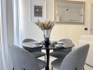 a table with chairs and a vase with flowers on it at The Boutique Houses Milan - Navigli in Milan
