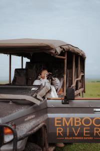Una donna che scatta una foto nel retro di un camion di Emboo River Camp a Talek