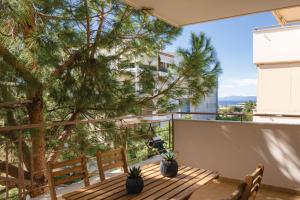einen Balkon mit einer Holzbank und einem Baum in der Unterkunft Elliniko Luxury Residence in Athen